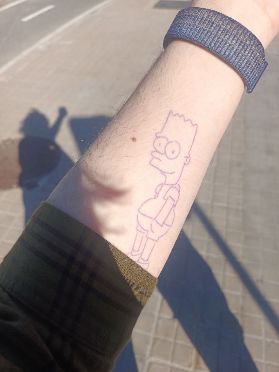 Un brazo con un tatuaje dibujado a boli de Bart Simpson